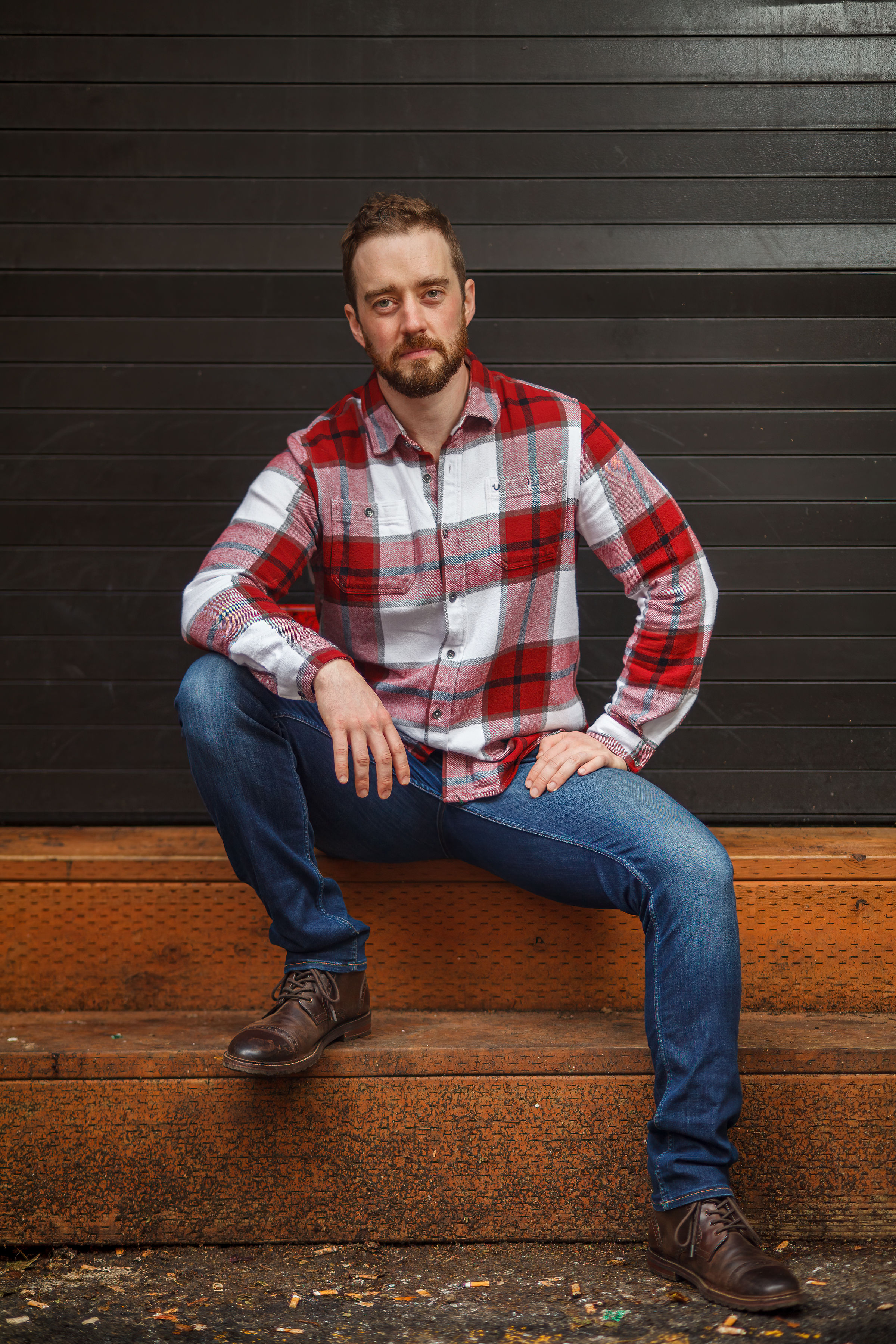 Adam Elliott Davis seated on a loading-dock step against a dark corrugated wall